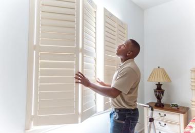 man-opening-wooden-window-shutters