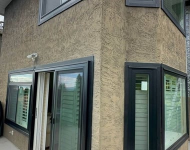 Black vinyl windows and sliding patio door installed on a stucco home in Vancouver