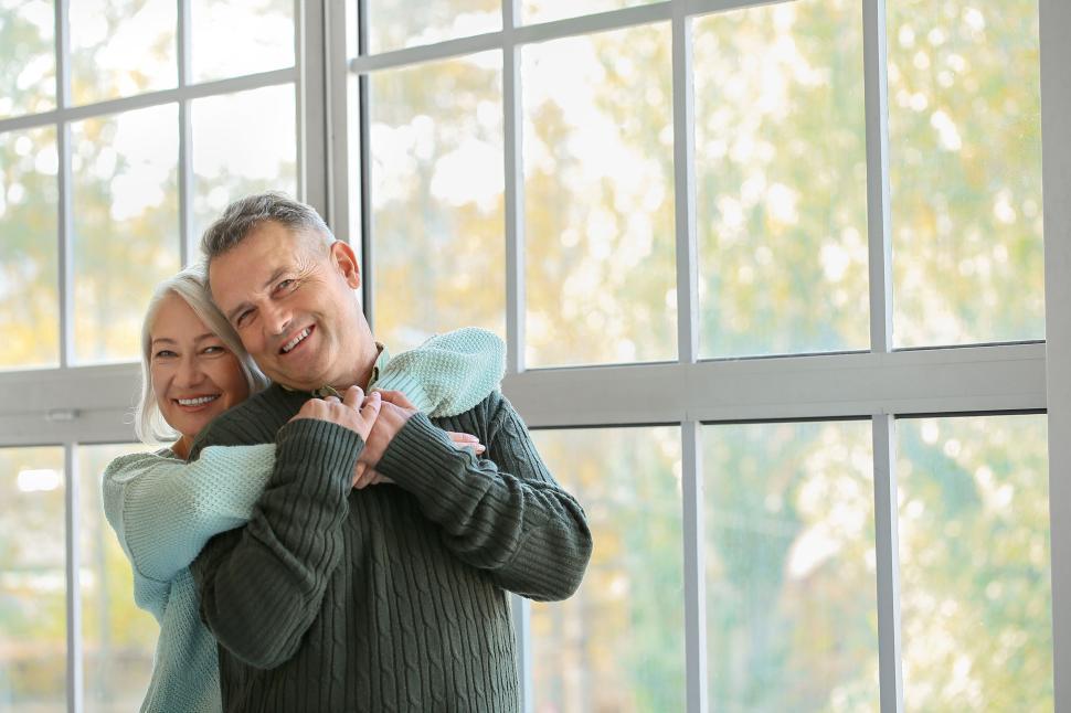 senior couple laughing and hugging by bright windows