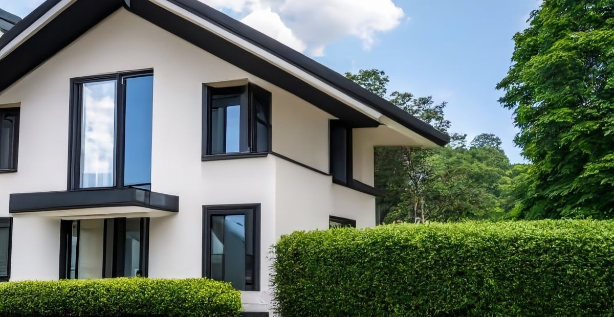 Modern Red Deer home with large windows, framed by hedges.